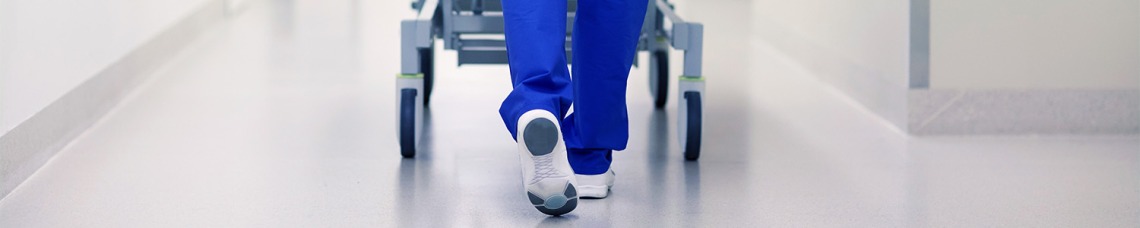 Nurse walking with hospital bed through hall